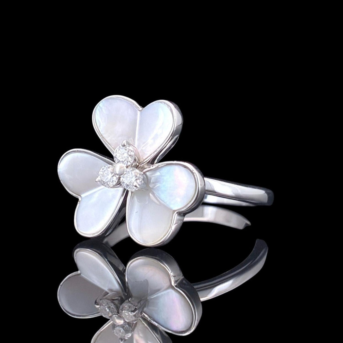 Impimo 0.15 CT moissanite and mother of pearl flower ring, 925 sterling silver with 18K white gold plating - the four-petal shell flower and band shown at an angle.