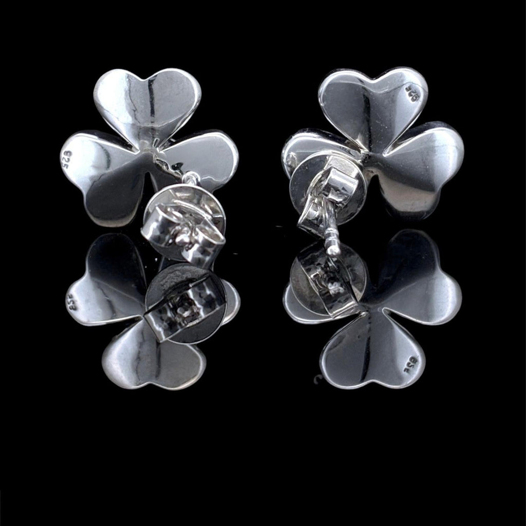Impimo mother of pearl and moissanite flower stud earrings - the pair at a lower angle, showing the petal profile and the flush-set centre stone.