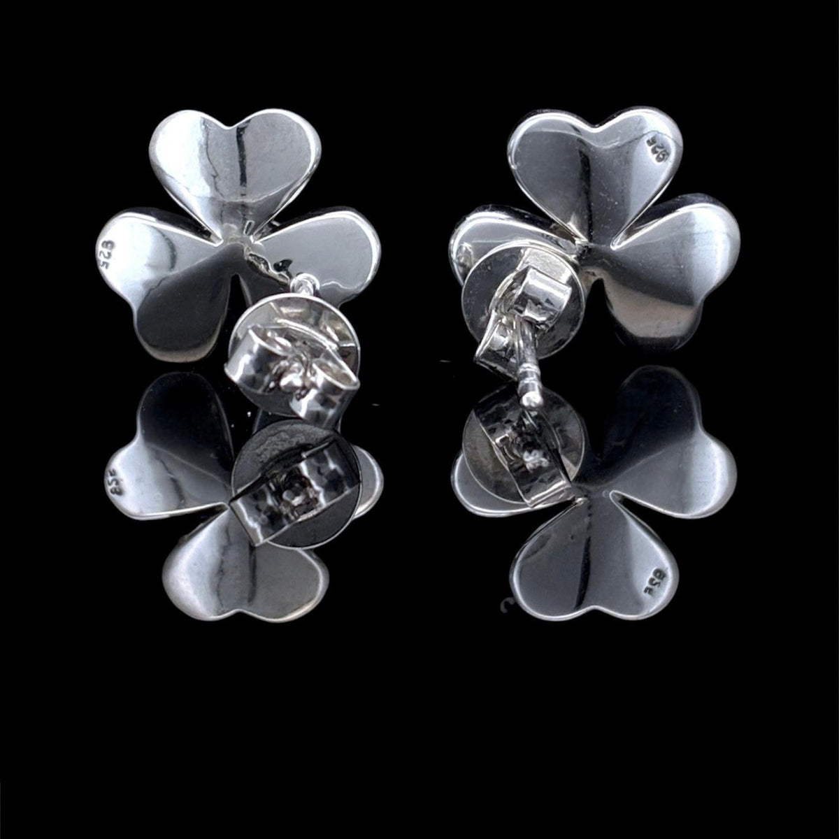 Impimo mother of pearl and moissanite flower stud earrings - the pair at a lower angle, showing the petal profile and the flush-set centre stone.