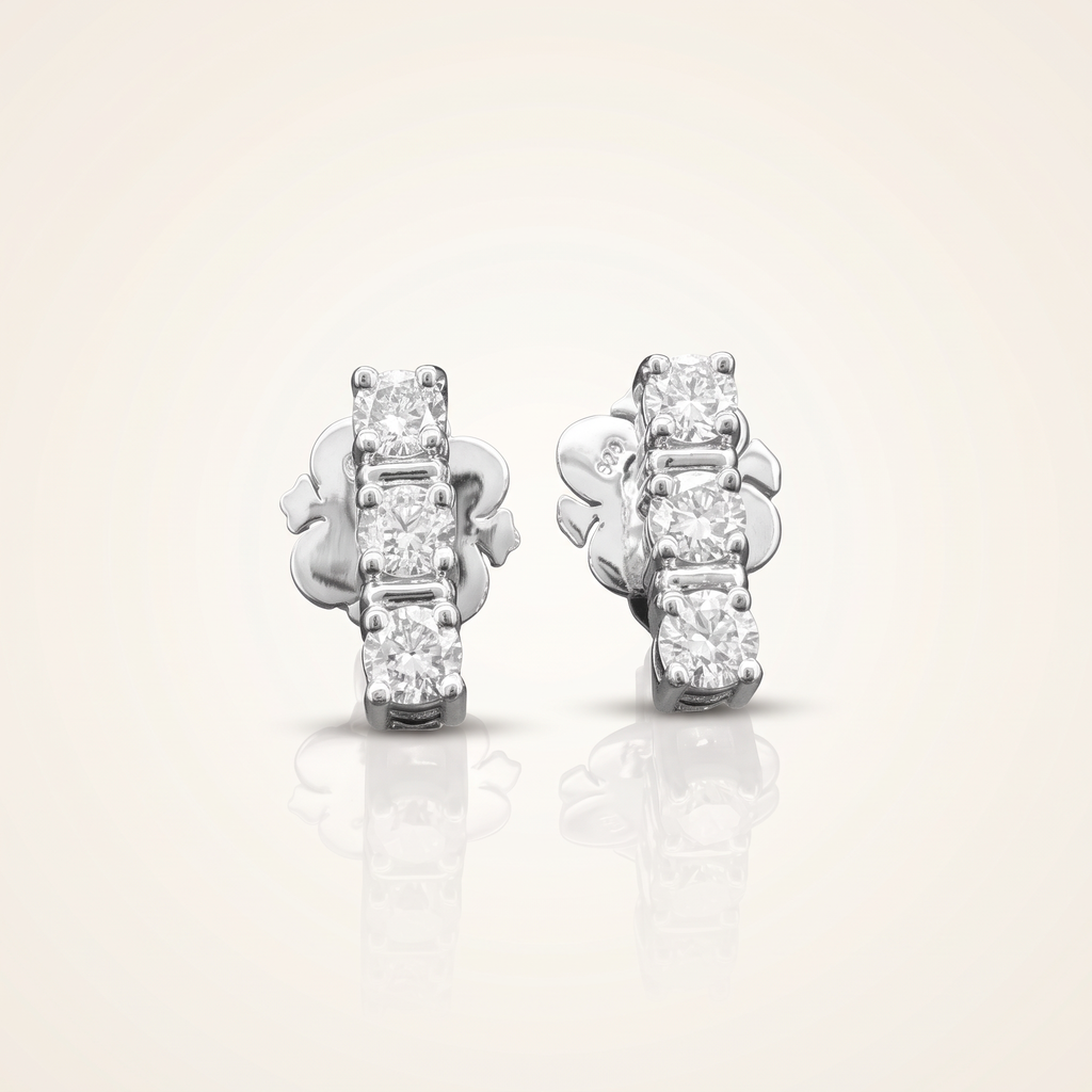 0.7 CT pair of lab-grown diamond round cut earrings in 925 sterling silver with 18K white gold plating, on a light ivory background