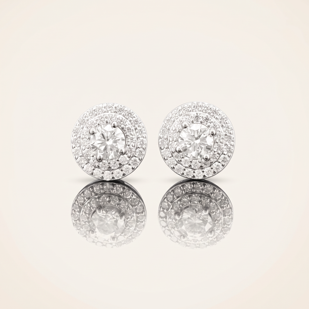 Pair of moissanite round cut earrings in 925 sterling silver with 18K white gold plating, on a light ivory background