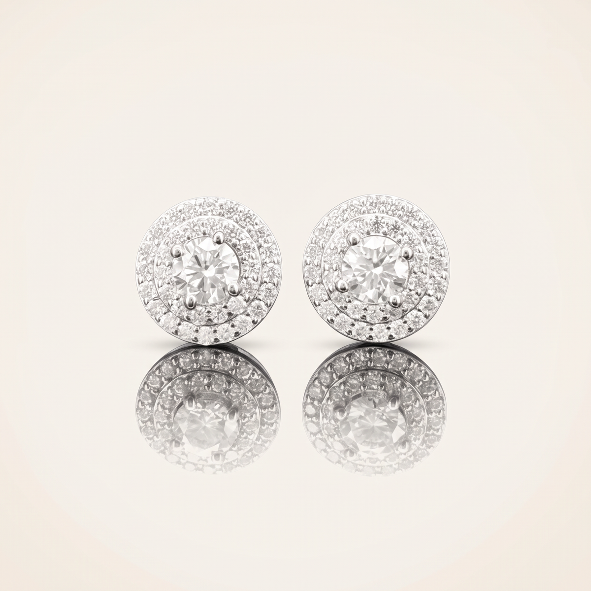 Pair of moissanite round cut earrings in 925 sterling silver with 18K white gold plating, on a light ivory background