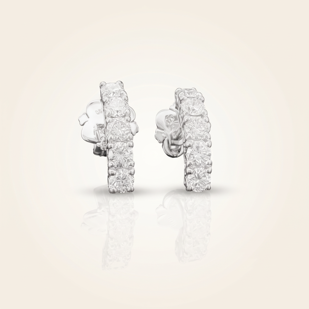 1.1 CT pair of lab-grown diamond round cut earrings in 925 sterling silver with 18K white gold plating, on a light ivory background