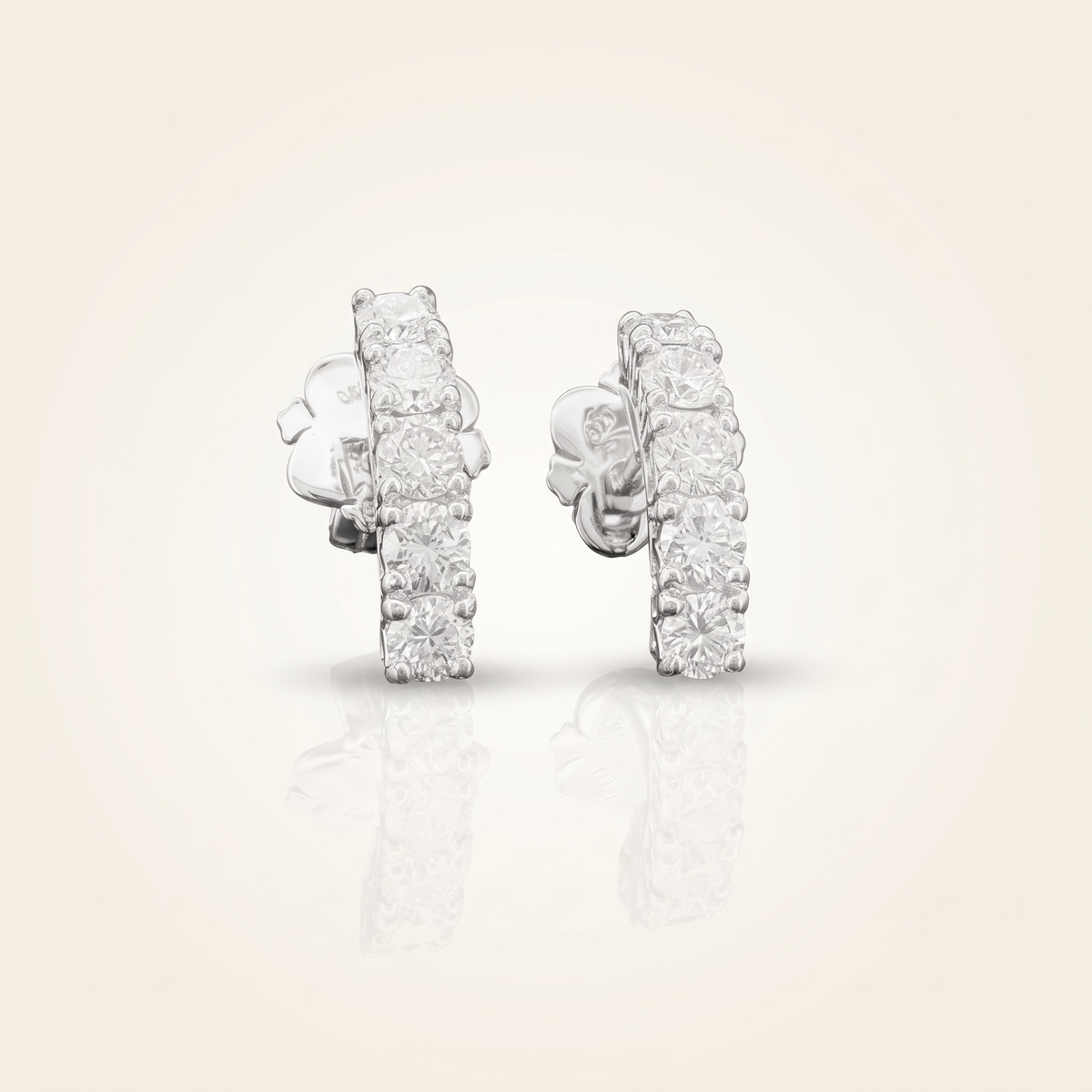 1.1 CT pair of lab-grown diamond round cut earrings in 925 sterling silver with 18K white gold plating, on a light ivory background