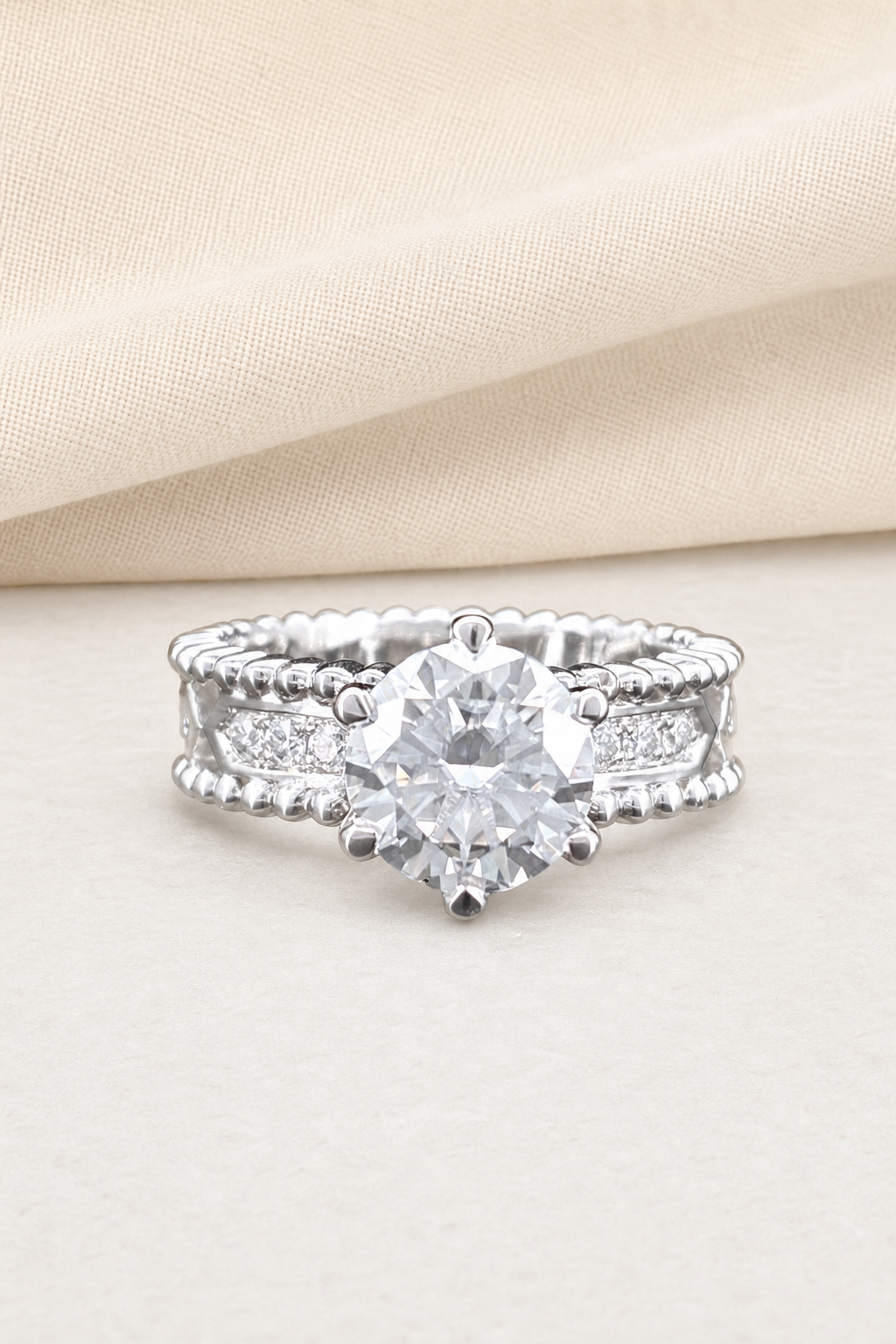 Impimo 1/2 CT Moissanite Round Solitaire Ring - Perlée Band - 925 Sterling Silver with 18K White Gold Plating | display view on ivory linen