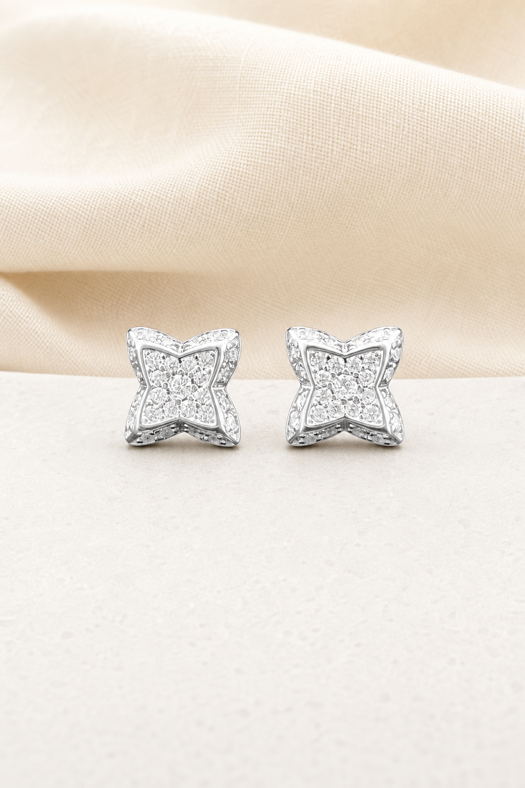 Impimo 0.3 CT (Pair) Moissanite Round Cut Earrings - Four-Point Star Pavé Stud - 925 Sterling Silver with 18K White Gold Plating | display view on ivory linen