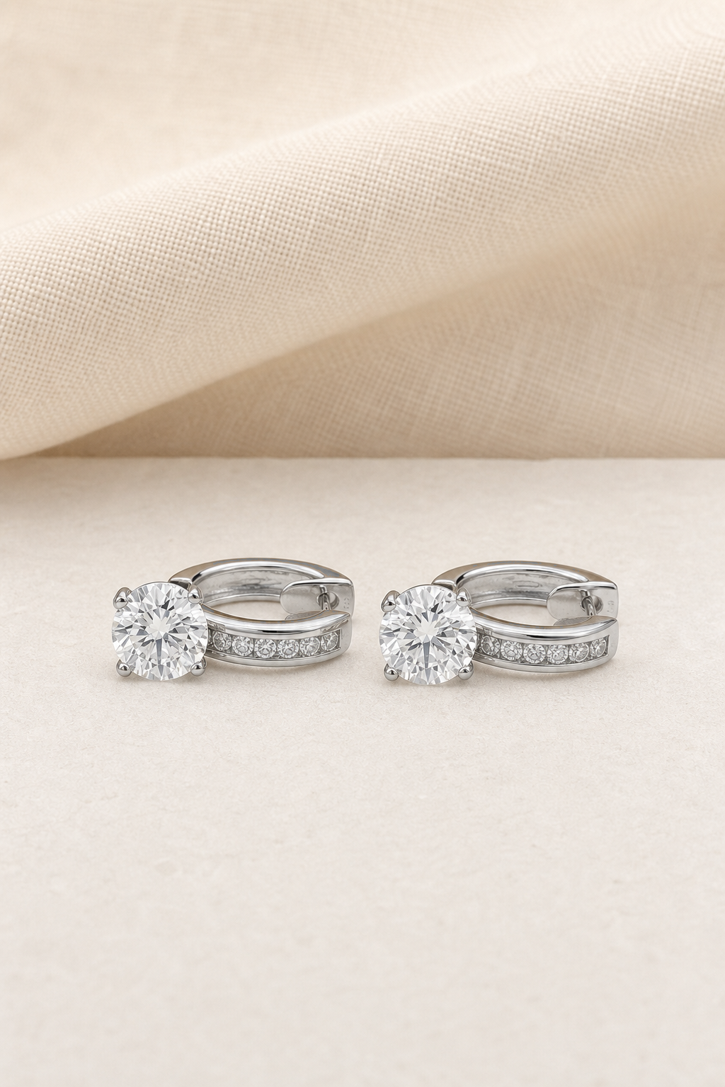 Impimo 4.5 CT (Pair) Moissanite Round Cut Earrings - Pavé Huggie Hoop with Drop - 925 Sterling Silver with 18K White Gold Plating | display view on ivory linen