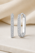 Impimo 0.15 CT (Total) Moissanite Round Cut Earrings - Elongated Pavé Huggie Hoop - 925 Sterling Silver with 18K White Gold Plating | display view on ivory linen