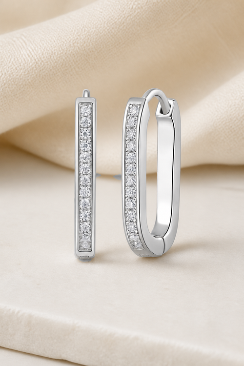 Impimo 0.15 CT (Total) Moissanite Round Cut Earrings - Elongated Pavé Huggie Hoop - 925 Sterling Silver with 18K White Gold Plating | display view on ivory linen