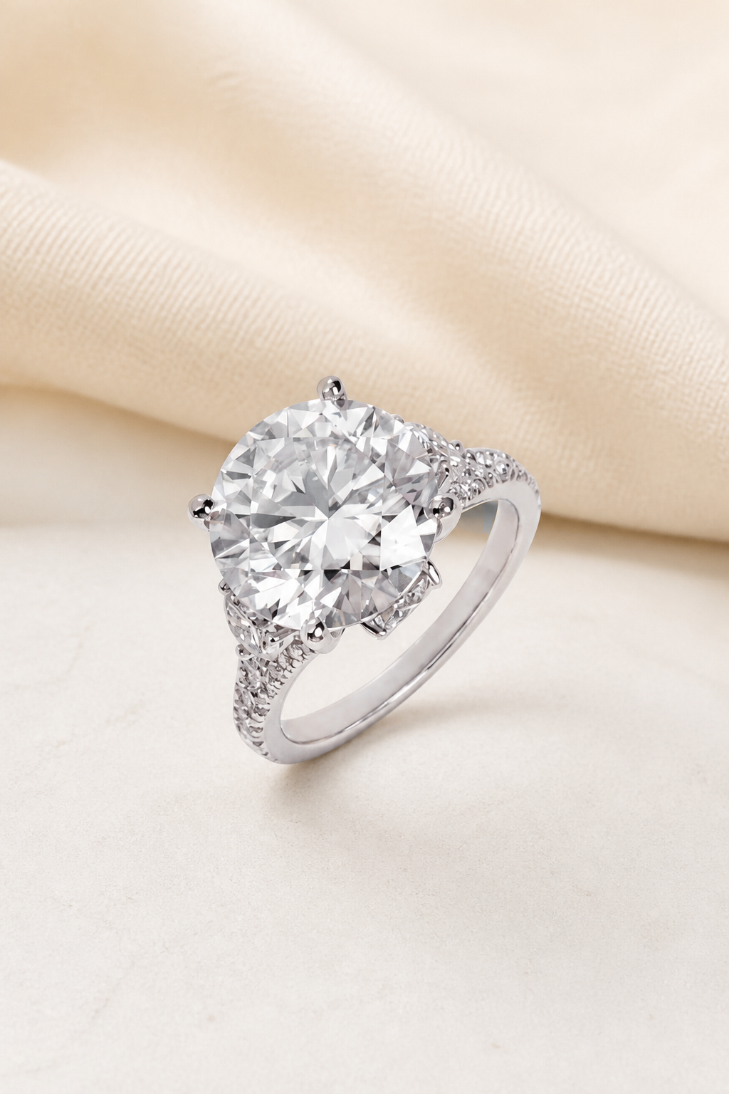 Impimo 10 CT Moissanite Round Cut Ring - Three-Stone Pavé Shank - 925 Sterling Silver with 18K White Gold Plating | display view on ivory linen