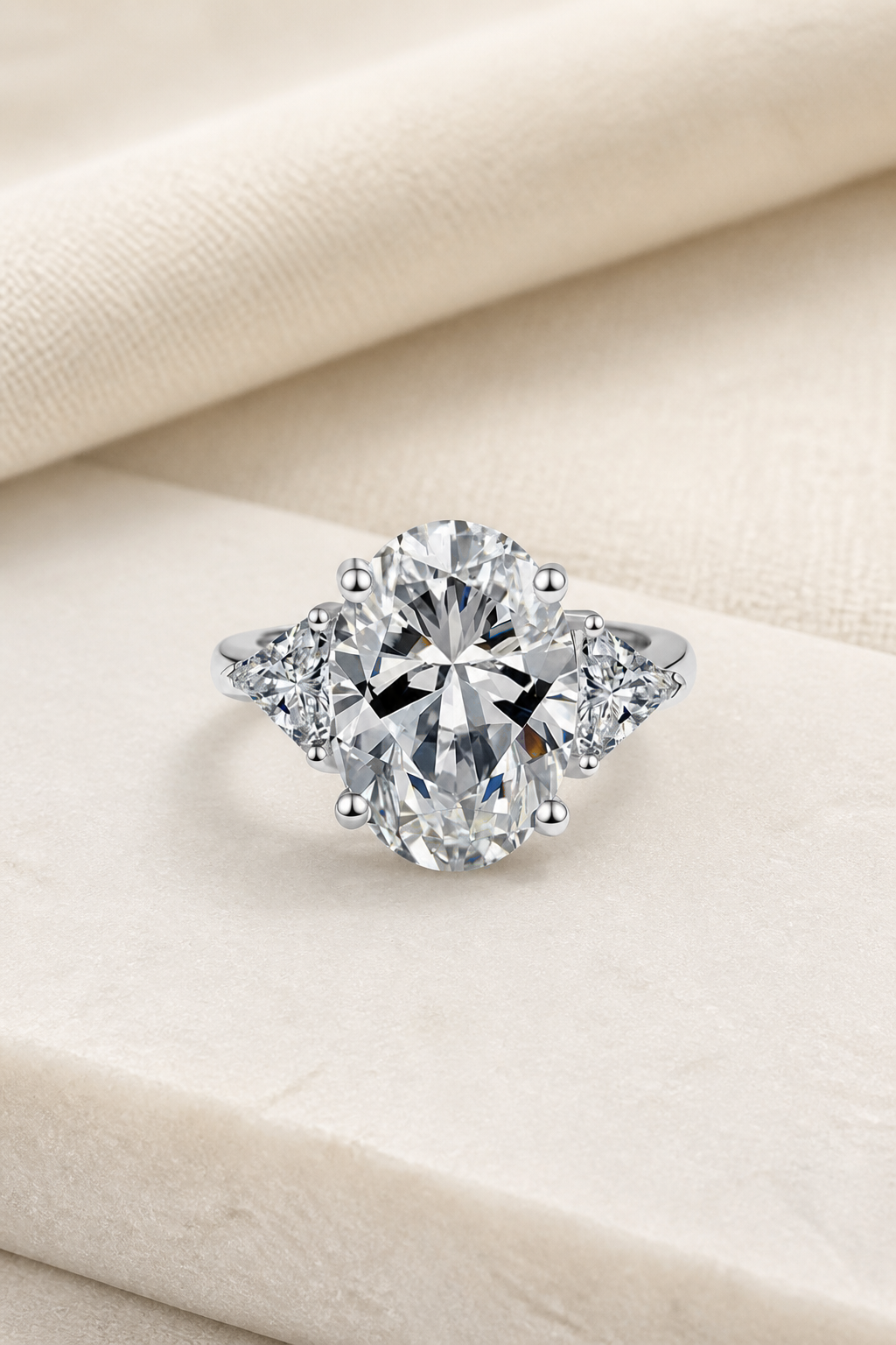 Impimo 8 CT Moissanite Oval Cut Ring - Three-Stone with 0.50 CT Trillion Sides - 925 Sterling Silver with 18K White Gold Plating | display view on ivory linen