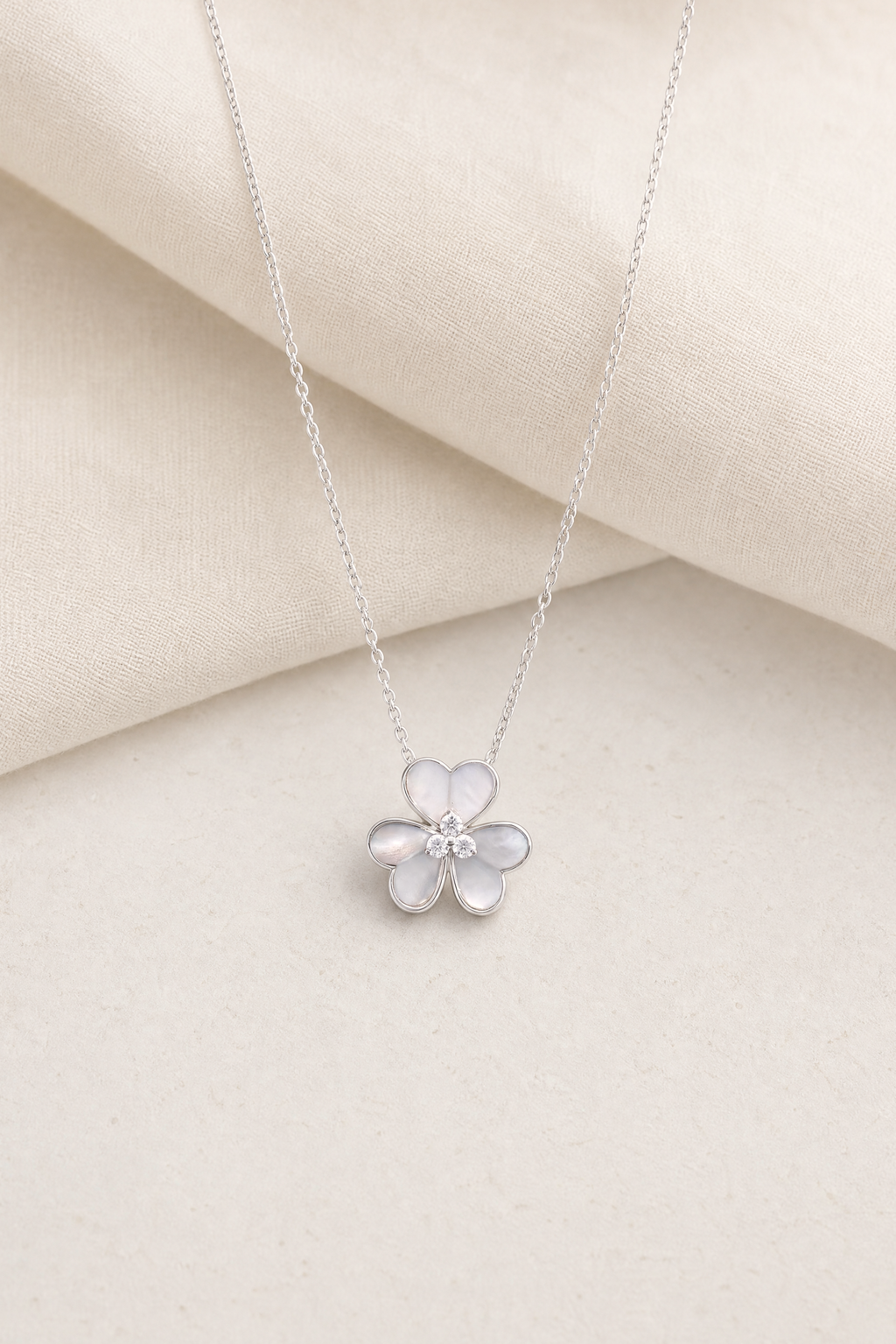 Impimo Natural Mother of Pearl & Moissanite Flower Pendant Necklace - 925 Sterling Silver with 18K White Gold Plating - display view on ivory linen